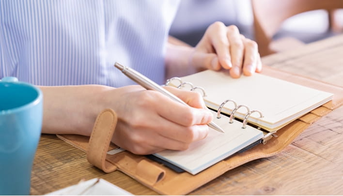 手帳にスケジュールを書き込む女性